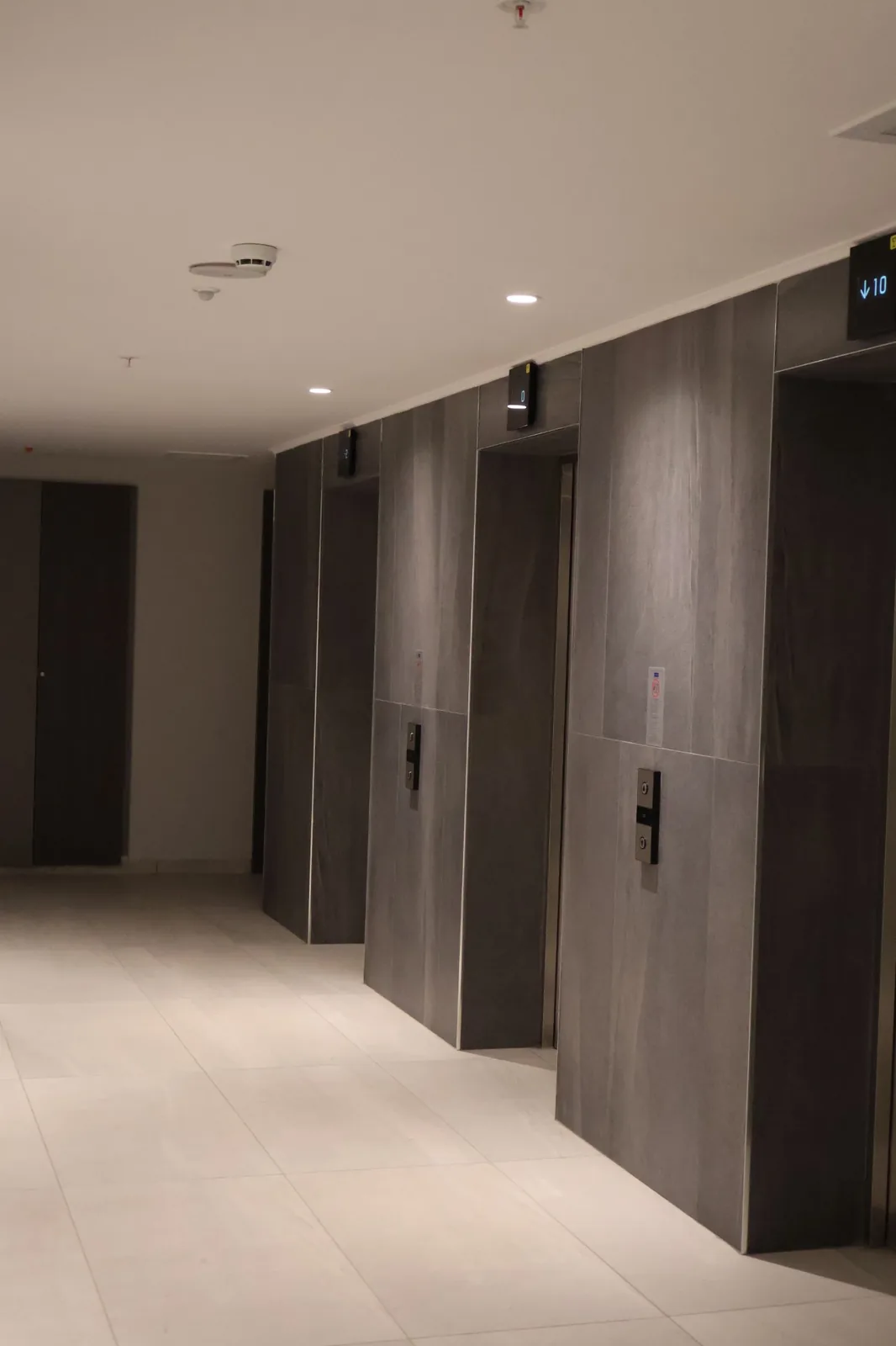 Tona Residence — Circulation cores: a quiet, even wash over stone-clad lift fronts makes wayfinding effortless.